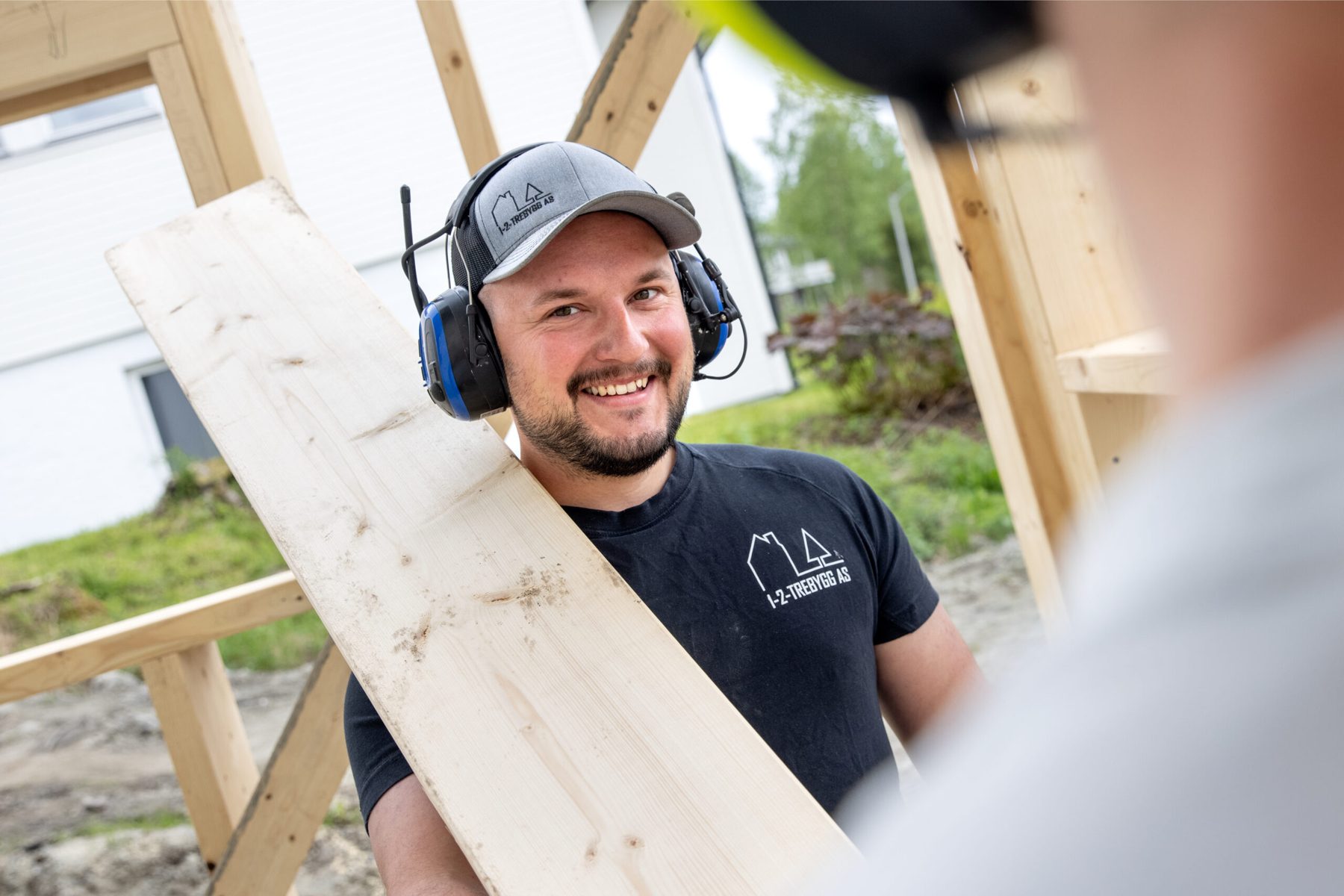 Tømrer bærer materialer på byggeplass